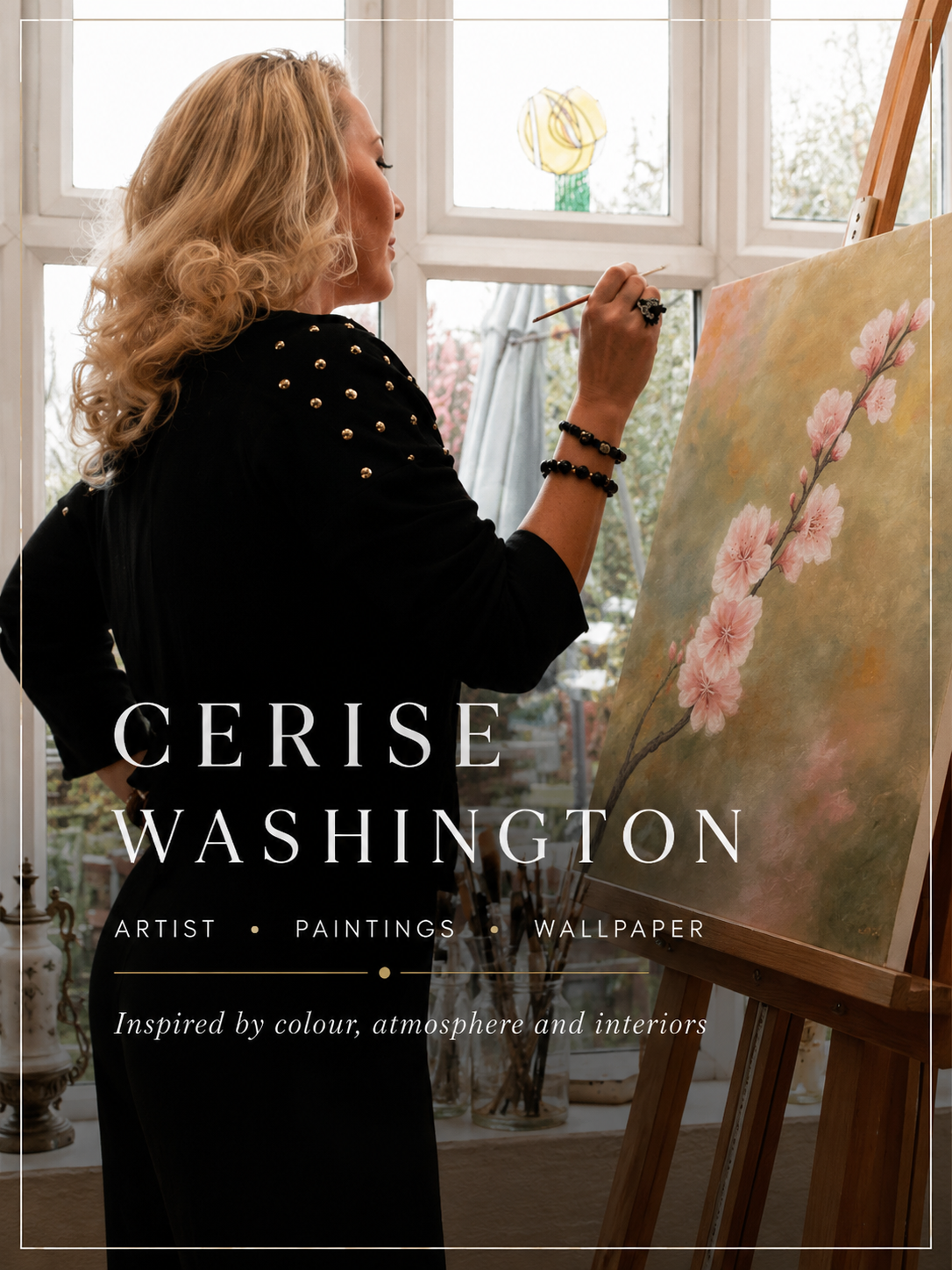 Cerise Washington painting a pink cherry blossom branch on a canvas at her easel beside a sunlit window